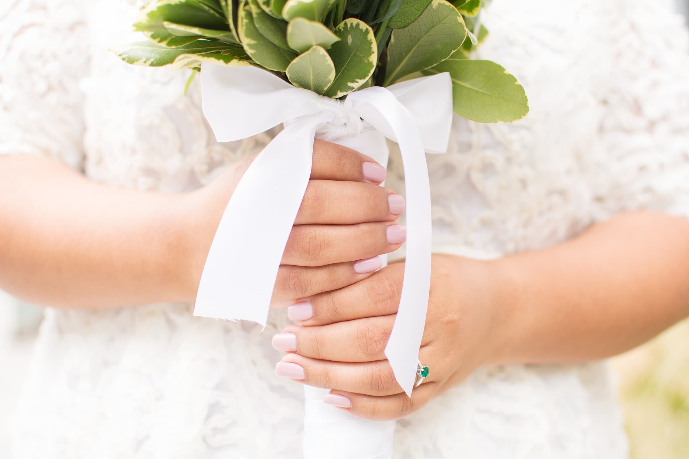 Close-up of a bride holding her bouquet with an emerald ring visible during a bright Tampa Bay elopement photography session.