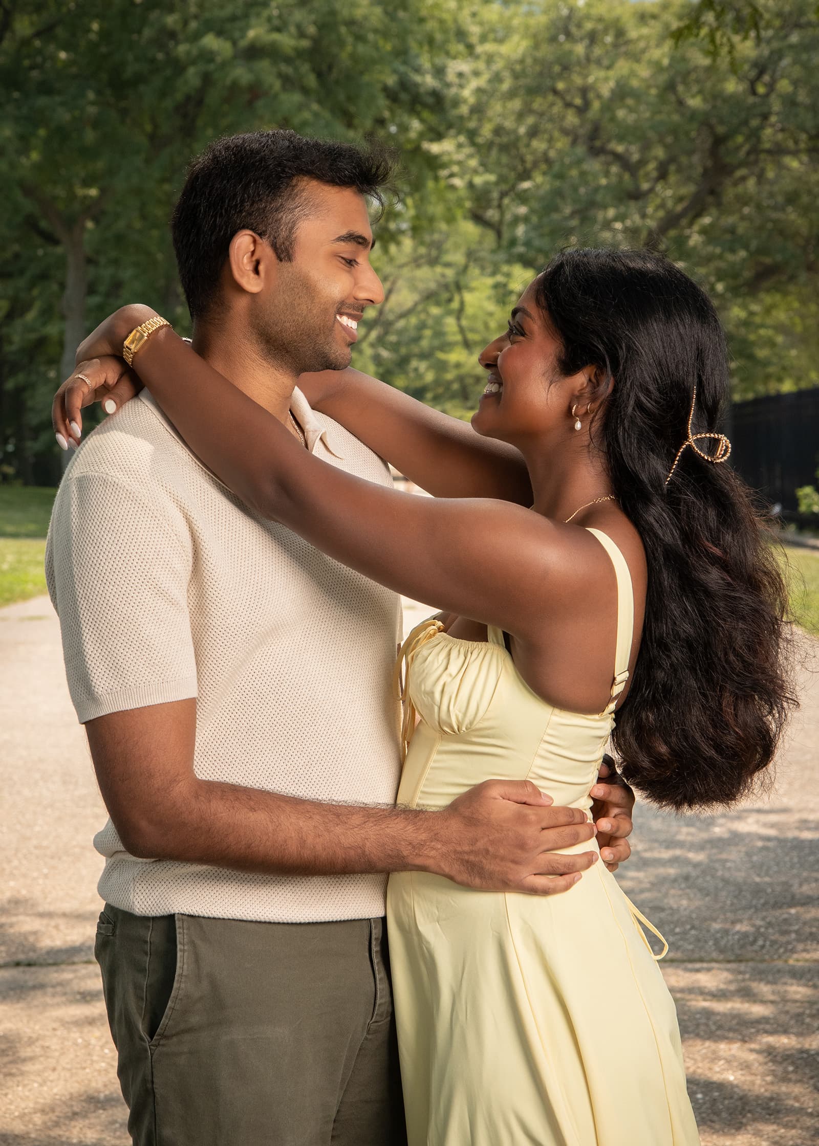Couple smiling at each other during a warm outdoor portrait session surrounded by trees and soft natural light in Tampa Bay.