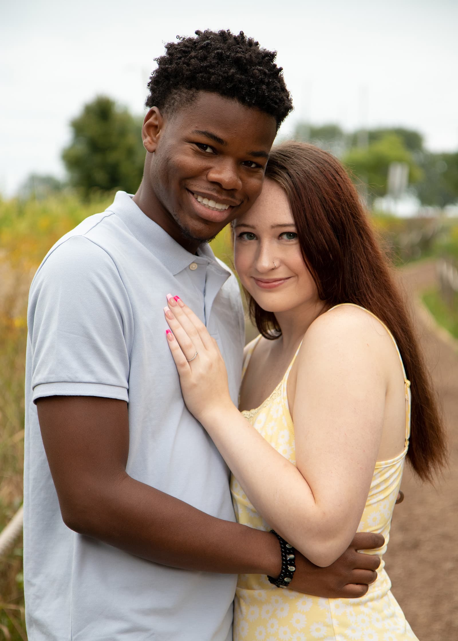 Smiling couple embracing in a wildflower garden during a relaxed outdoor portrait session with soft natural light.