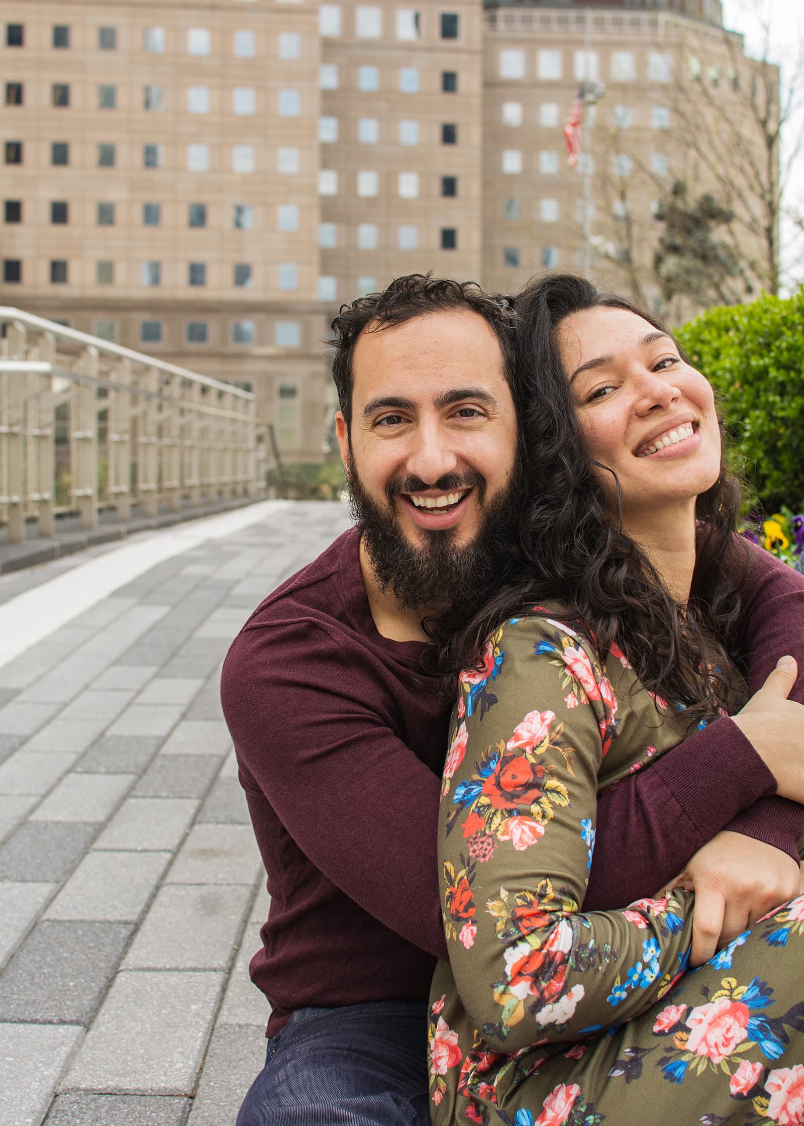 Smiling couple embracing during a relaxed outdoor portrait session in Tampa Bay, photographed with a natural urban backdrop.