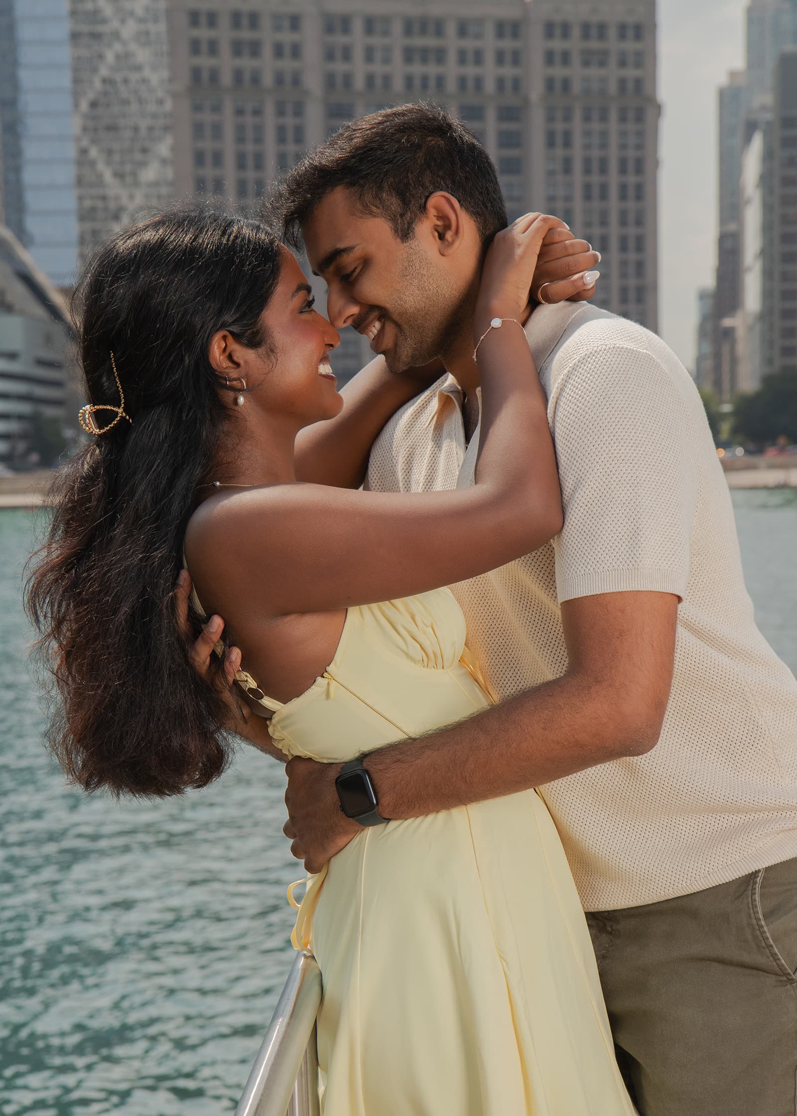 Couple embracing by the waterfront with city buildings behind them during a romantic outdoor portrait session in Tampa Bay.