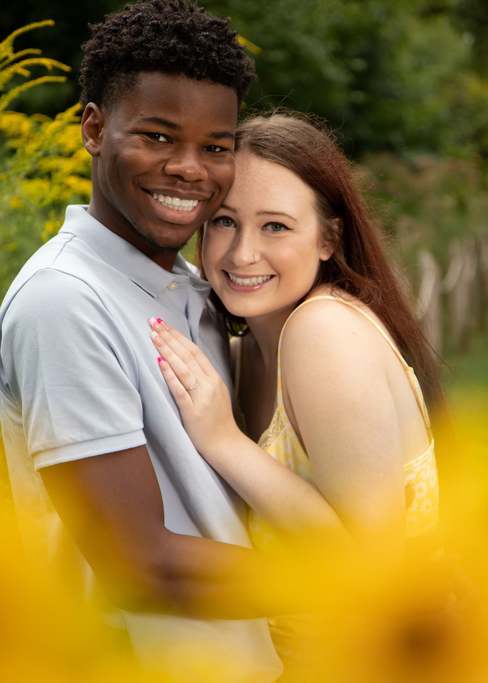 Smiling couple embracing among yellow wildflowers during a warm and natural outdoor couples portrait photography session.