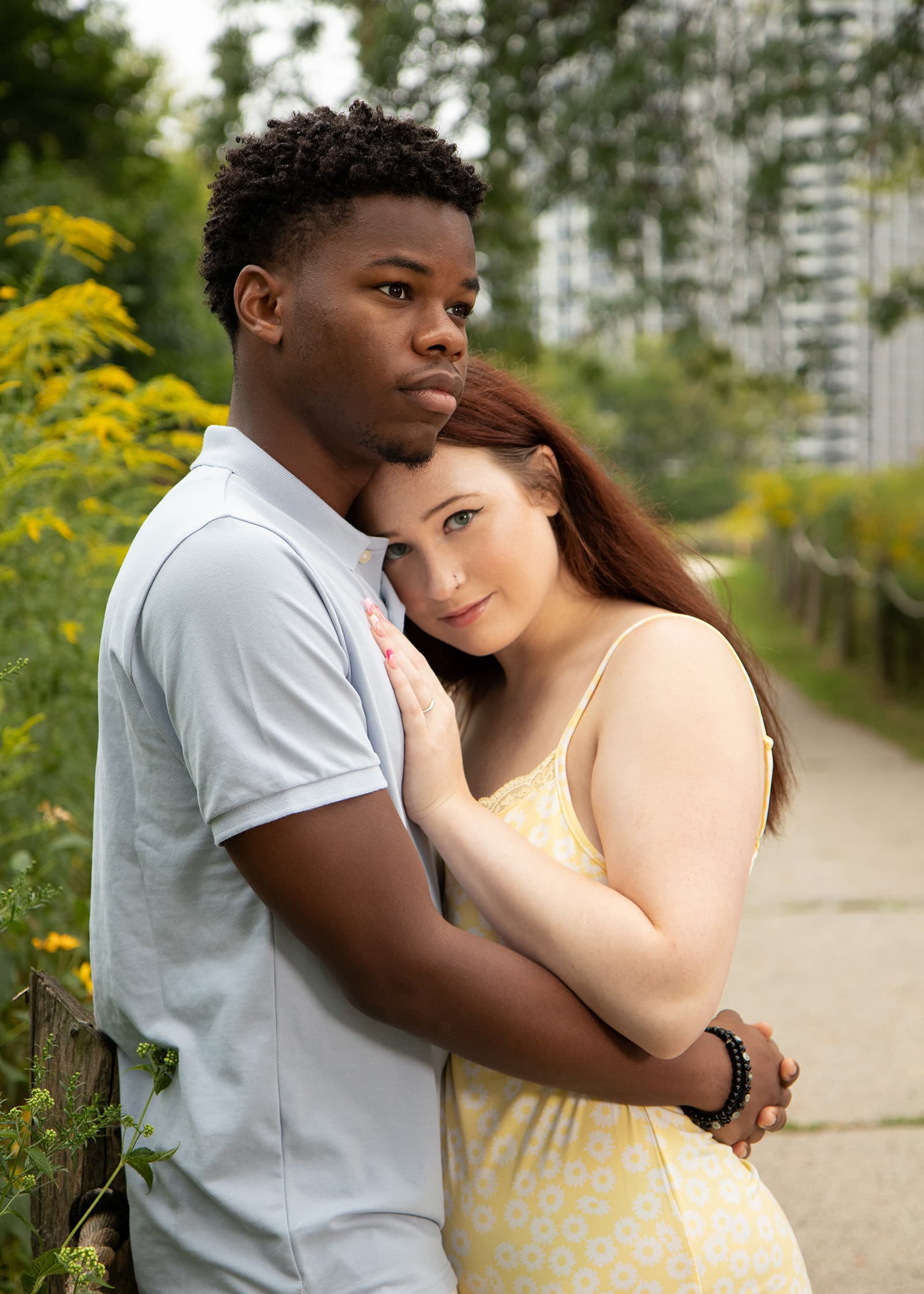 Couple embracing along a garden path during a relaxed outdoor portrait session surrounded by greenery and wildflowers.