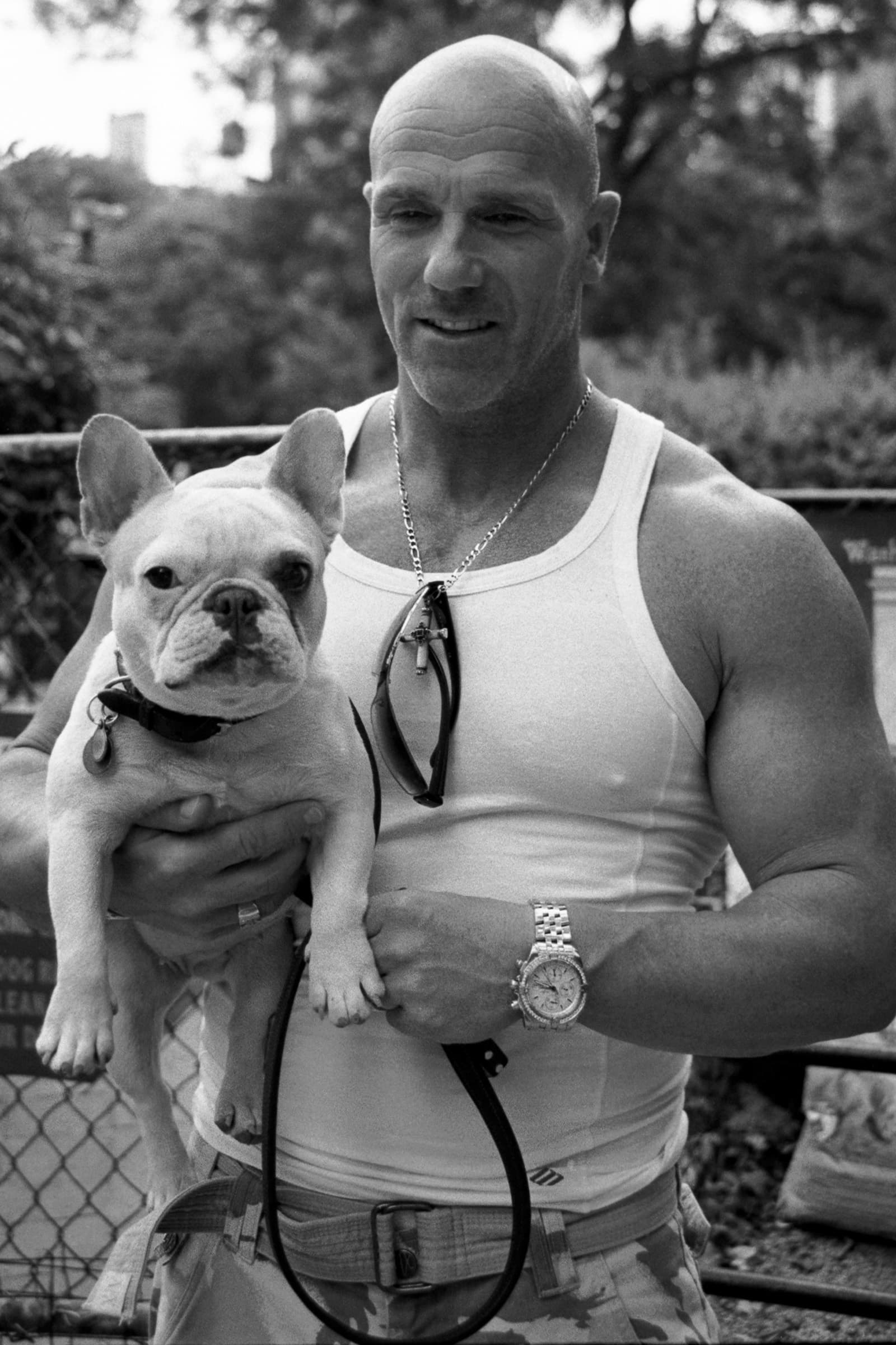 Man holds his French Bulldog for a close black-and-white Tampa dog photography portrait with a softly blurred park backdrop.