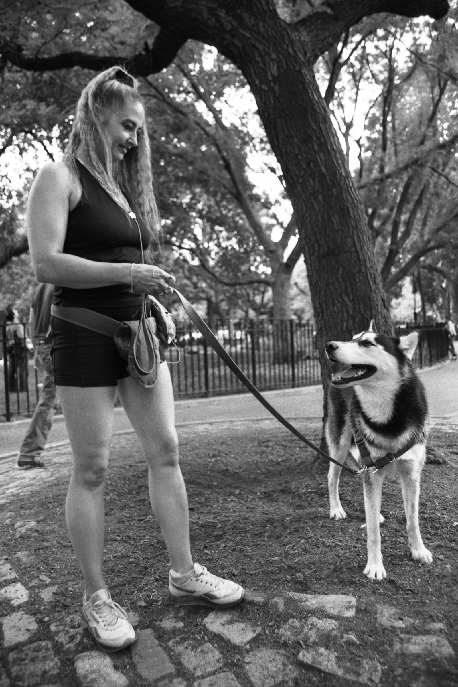 Woman smiles at her Siberian Husky on a leash beneath oak trees during an outdoor portrait photography session in Tampa.