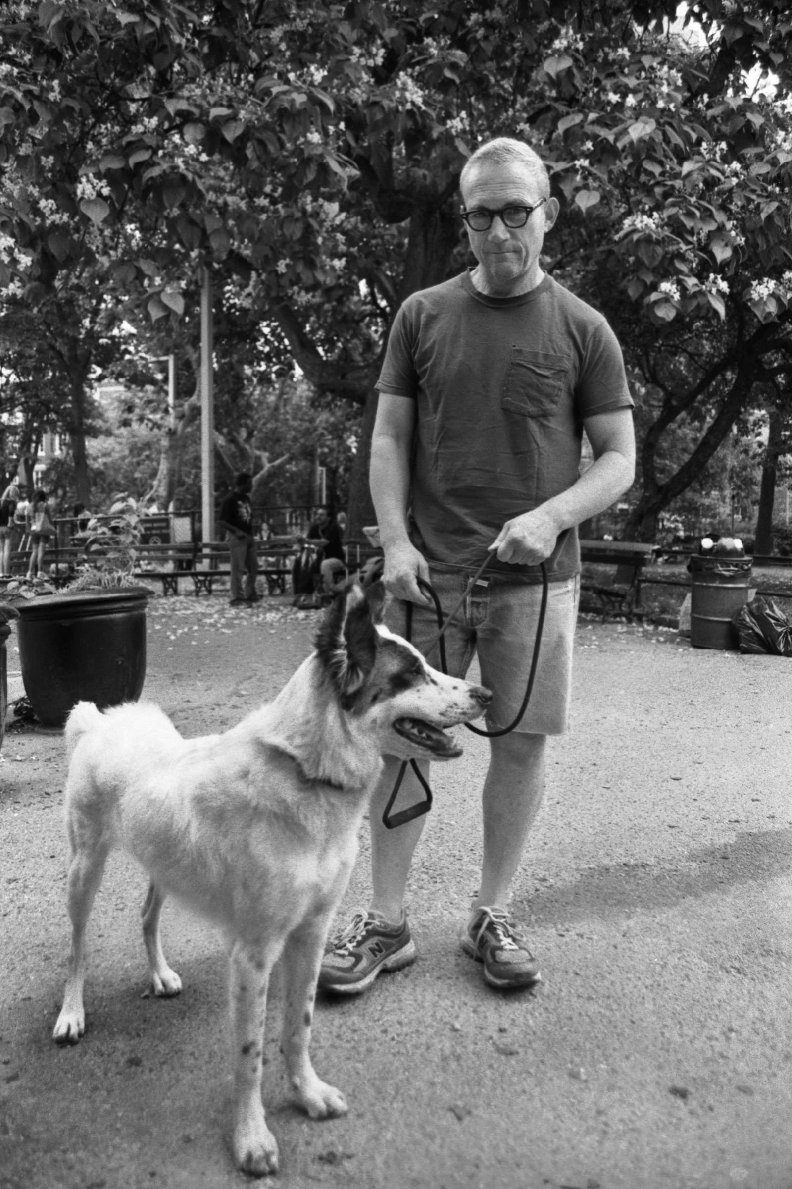 Man stands with his dog on a leash in a Tampa park during a natural black-and-white pet portrait focused on their bond.
