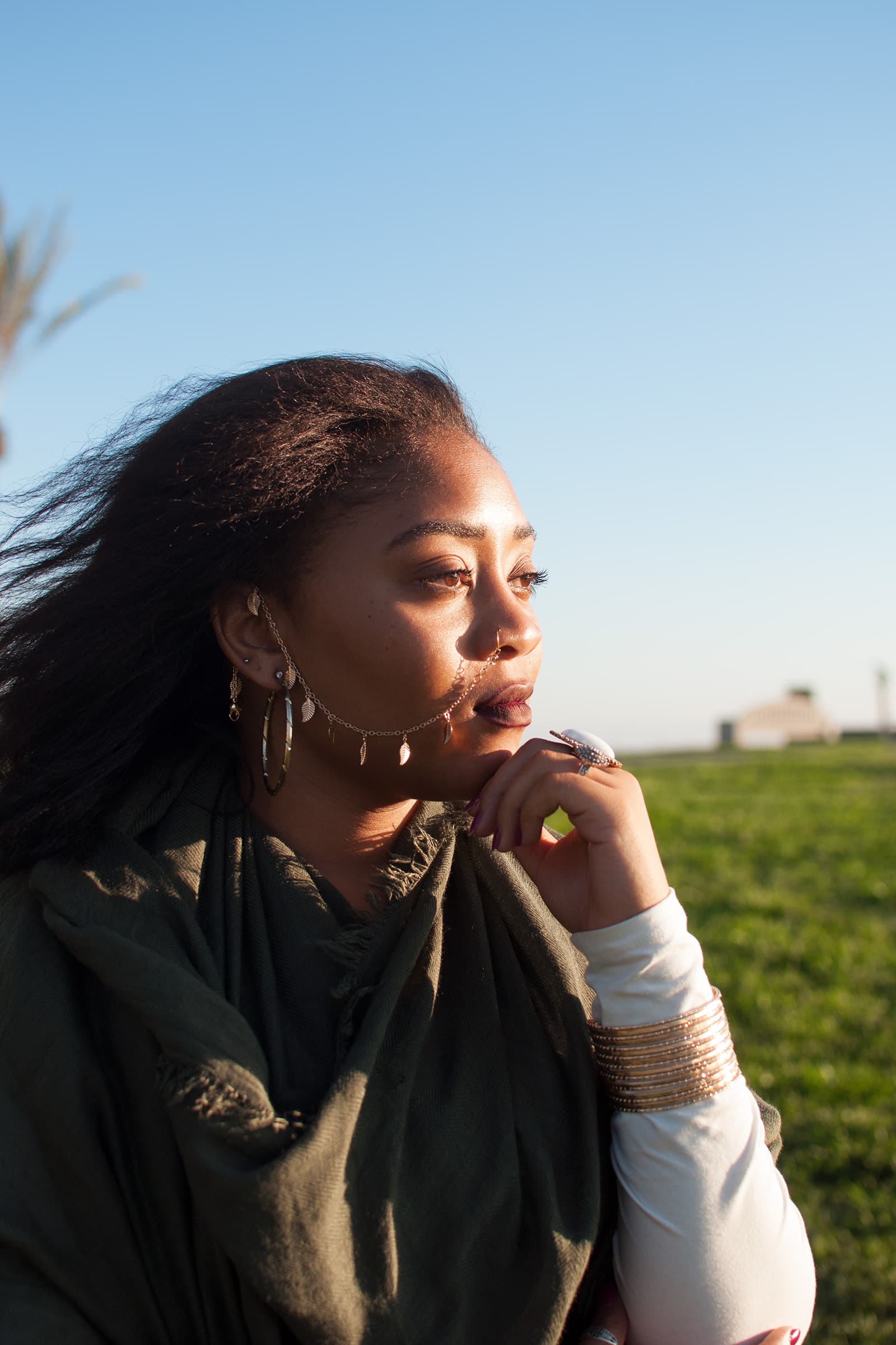 Muslims of America portrait of a Black Muslim woman wearing statement jewelry and a dark green scarf in evening light.