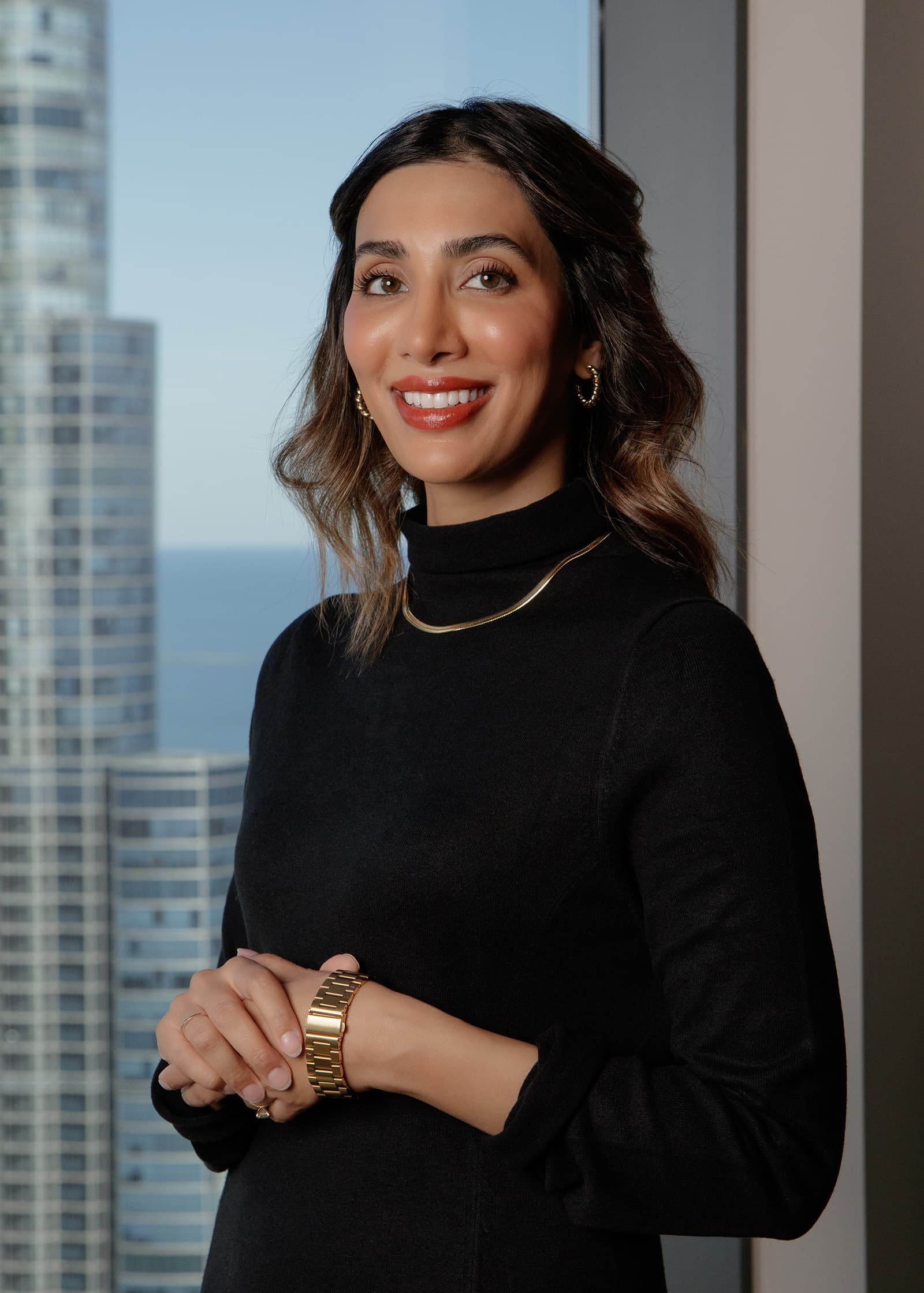 Professional portrait of a smiling woman in black with high-rise buildings softly visible through a Tampa window.