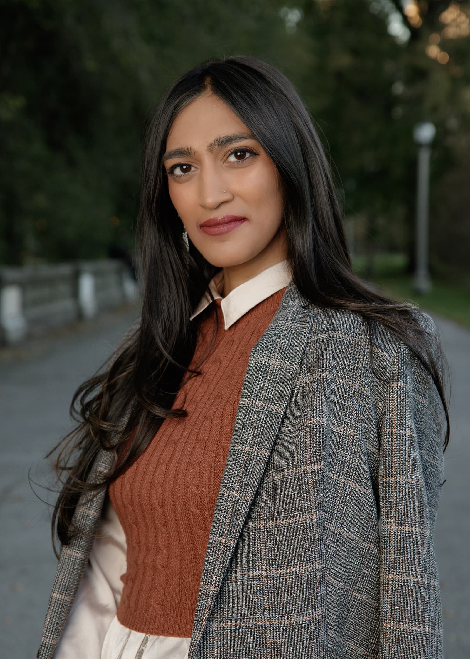 Professional outdoor portrait of a woman in layered business attire with a softly blurred green Tampa background.