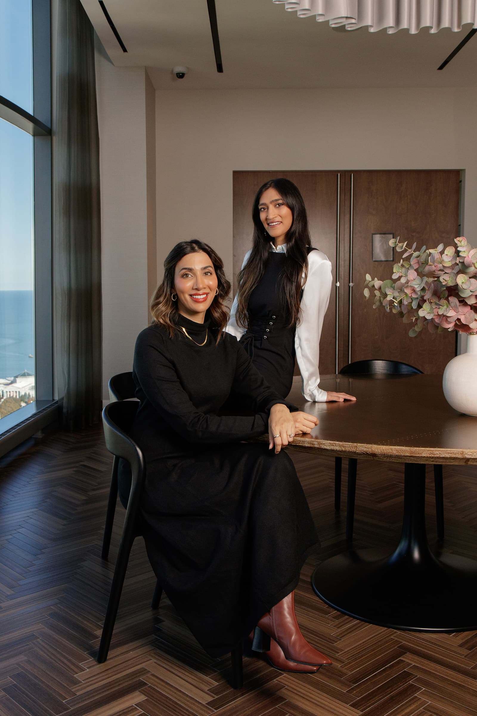 Business portrait of two professional women posed beside a table in a refined modern interior in the Tampa Bay area.