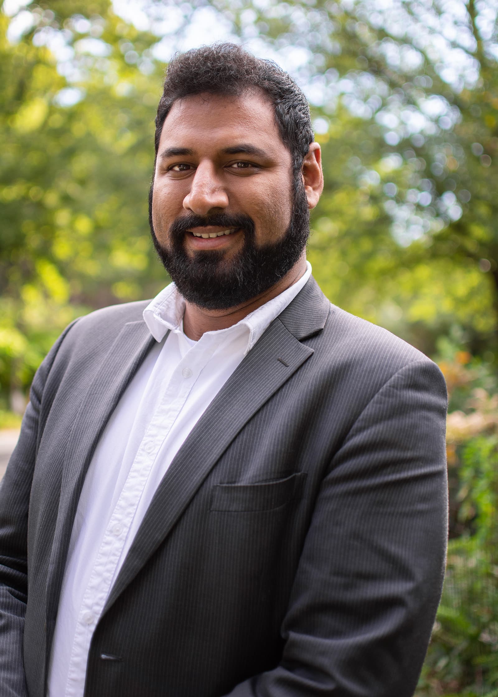 Professional outdoor portrait of a bearded man in a gray suit and white shirt, photographed in the Tampa Bay area.