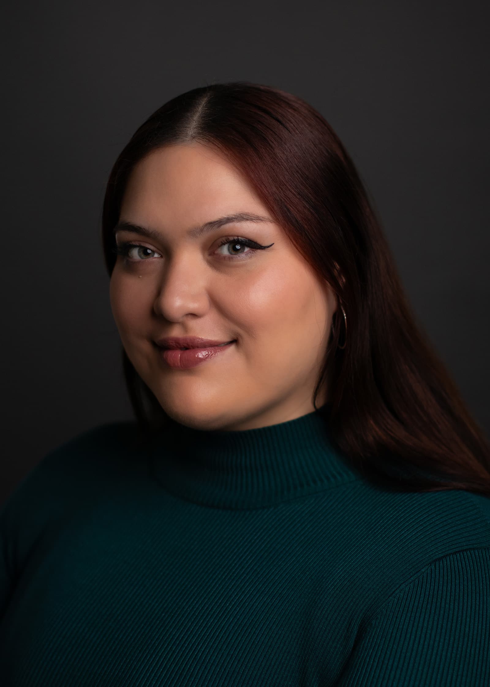 Professional studio headshot of a woman in a dark green top with soft lighting against a charcoal Tampa backdrop.