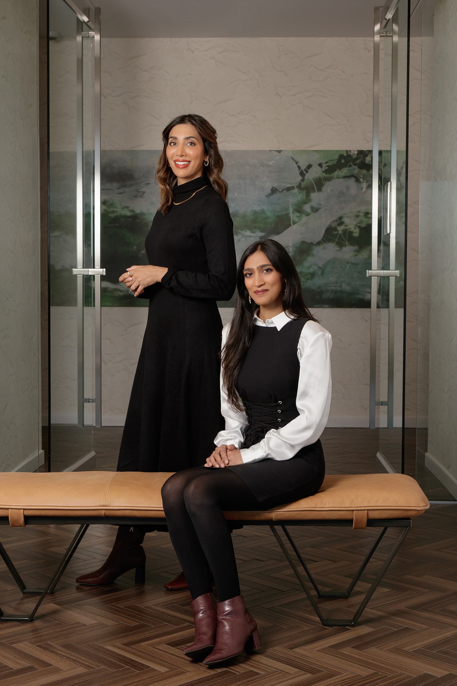 Professional portrait of two women in polished business attire posed in a contemporary Tampa Bay office interior.