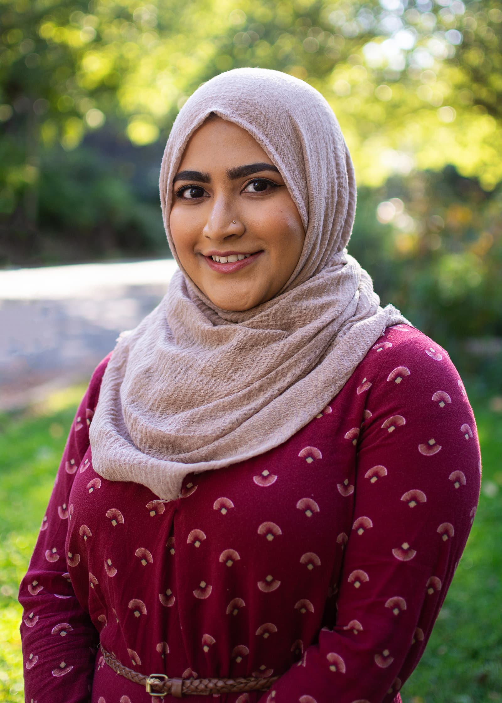Professional outdoor portrait of a woman in a neutral hijab and burgundy dress, photographed in the Tampa Bay area.