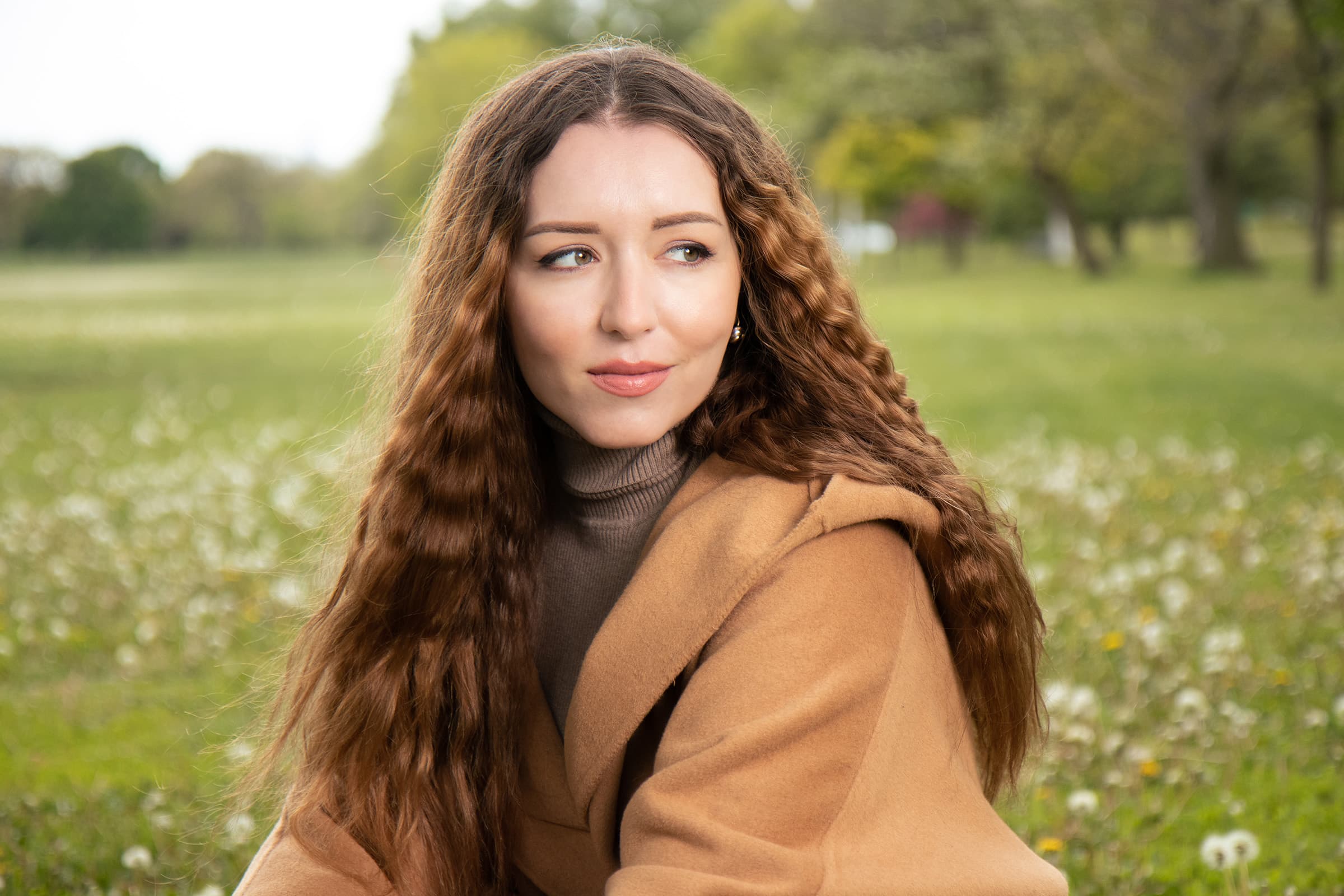 Outdoor professional portrait of a woman in a camel coat, photographed in Tampa with soft flash and natural light.