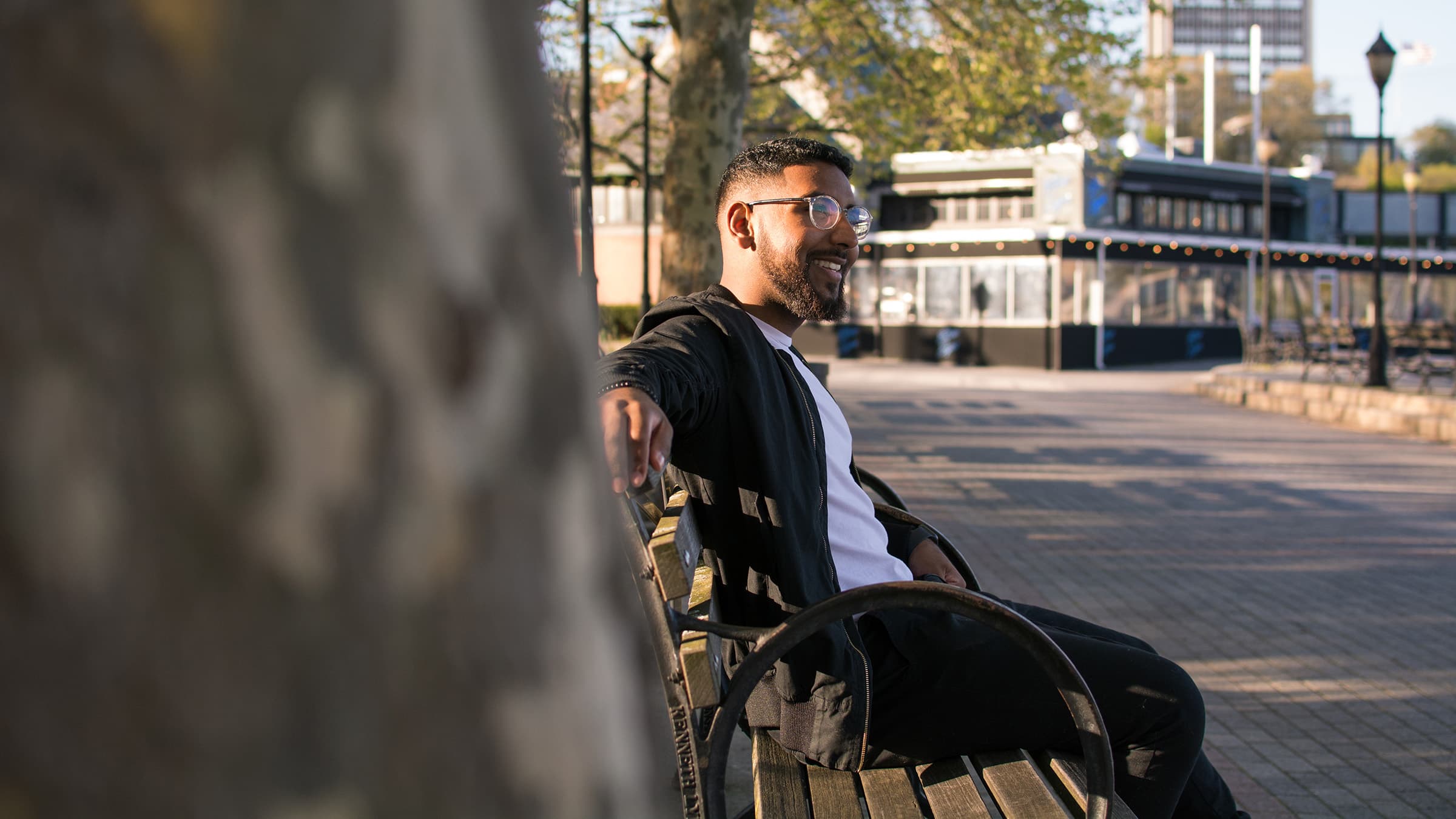 Outdoor professional portrait of a smiling man seated on a bench in Tampa, photographed with soft natural afternoon light.