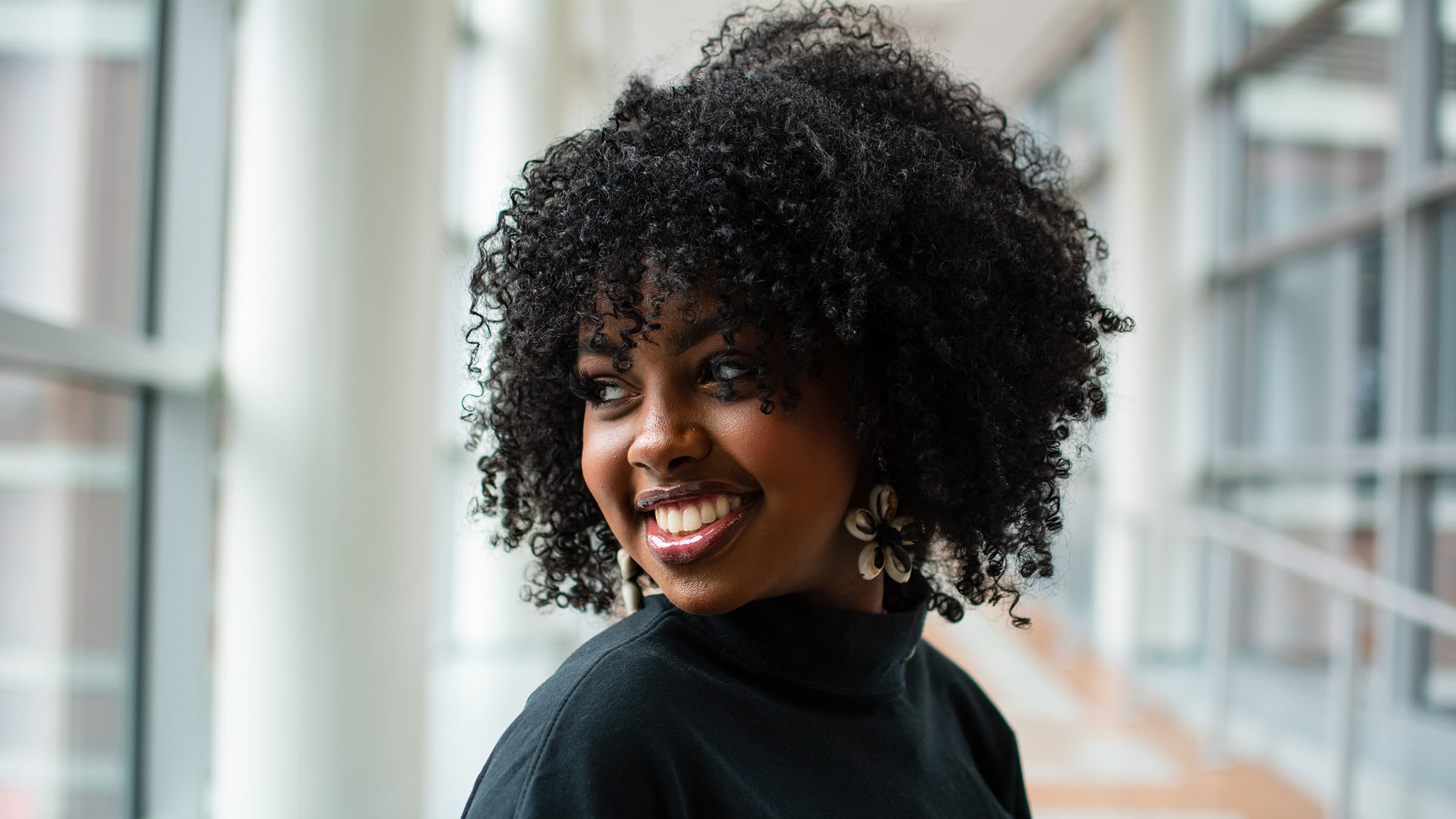 Professional indoor headshot of a smiling woman with natural curls, photographed in Tampa with soft window light.