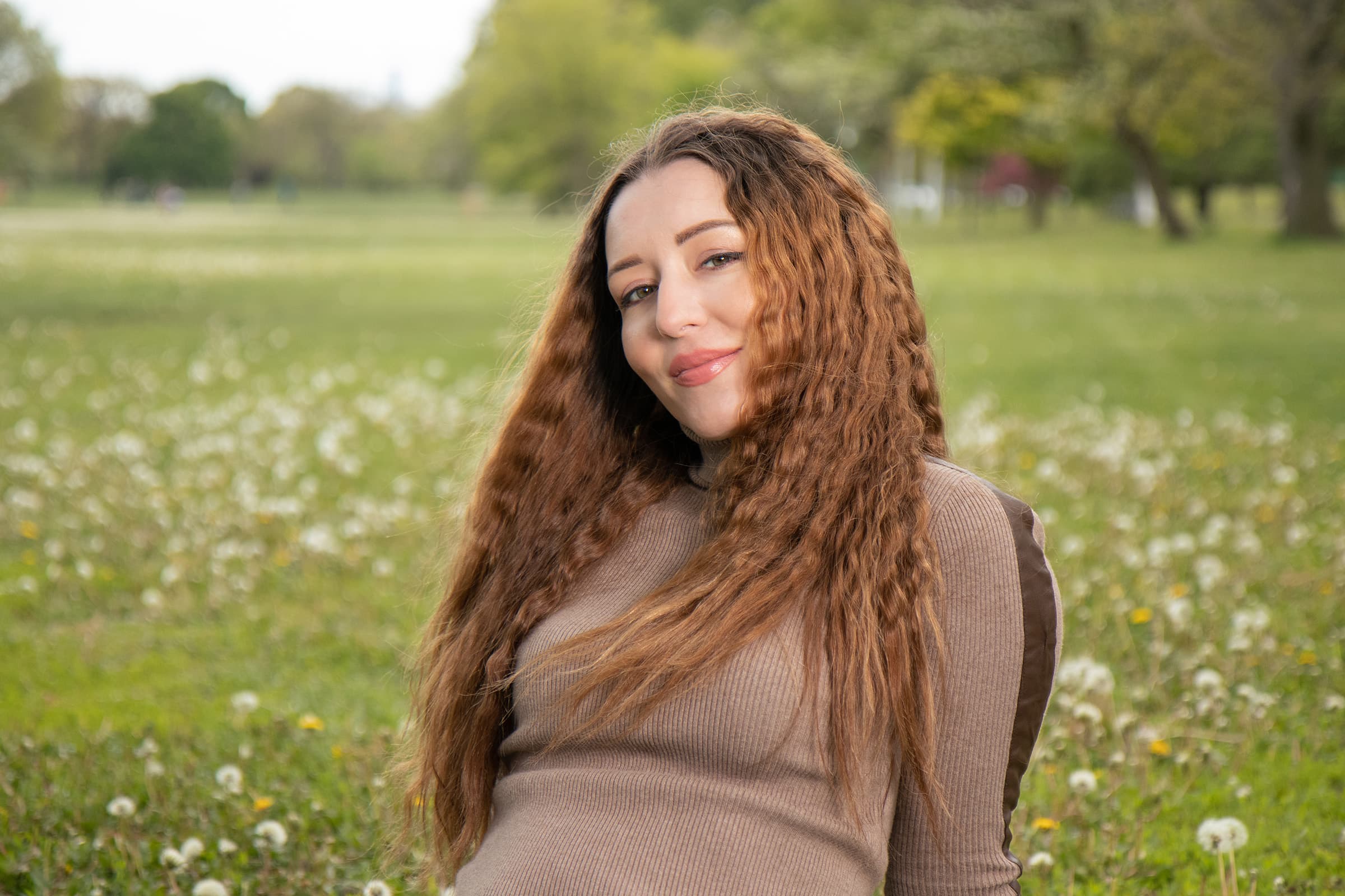 Outdoor portrait of a professional woman in Tampa, seated in a green field and photographed with soft natural light.