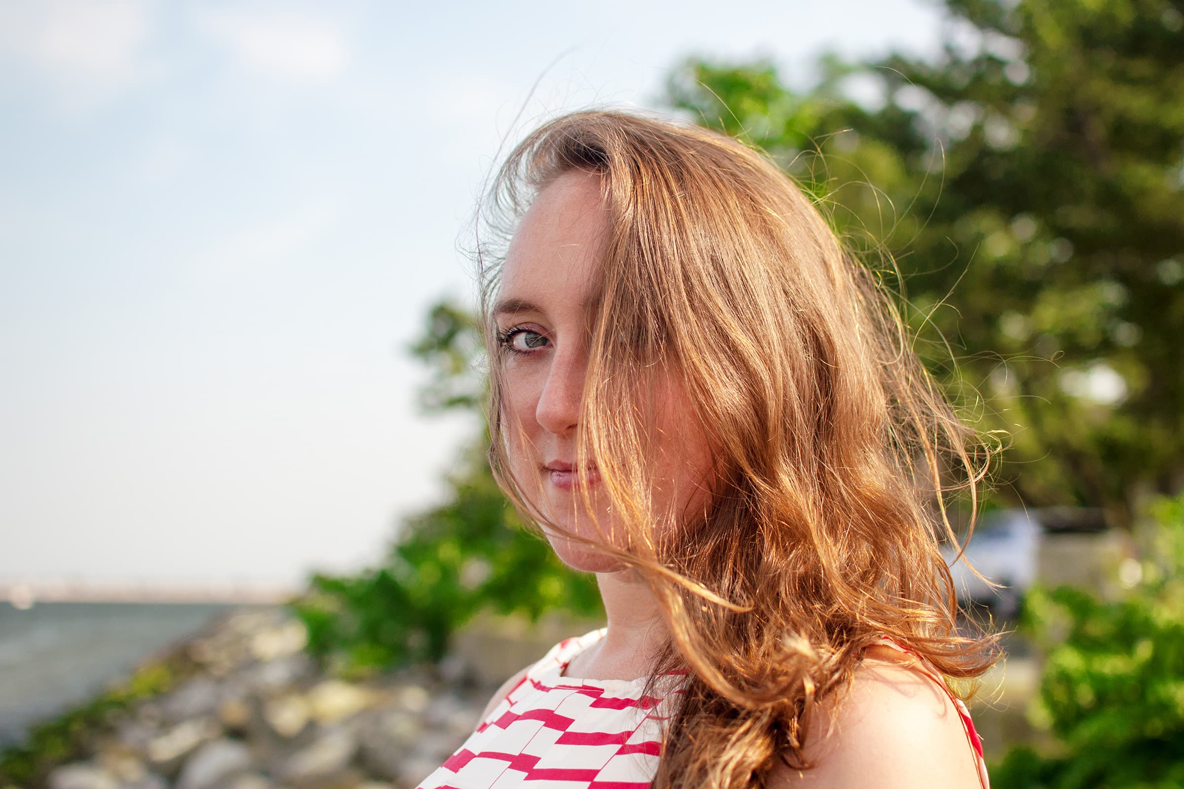 Cinematic waterfront portrait of a woman in Tampa, photographed with warm natural light and windswept hair.
