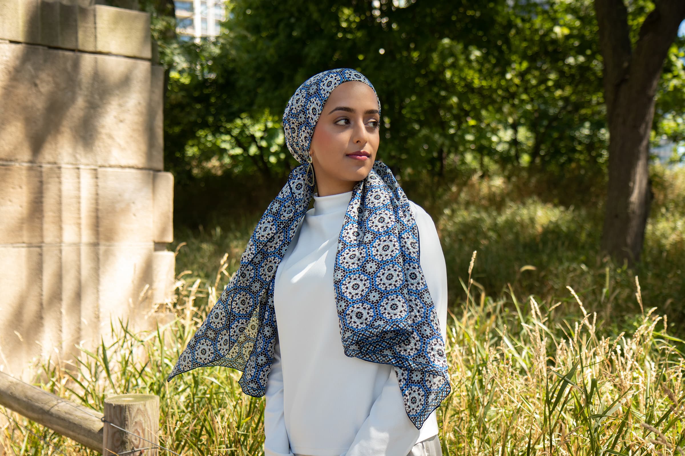 Outdoor portrait of a woman in a patterned hijab, photographed with natural light in a lush Tampa park setting.