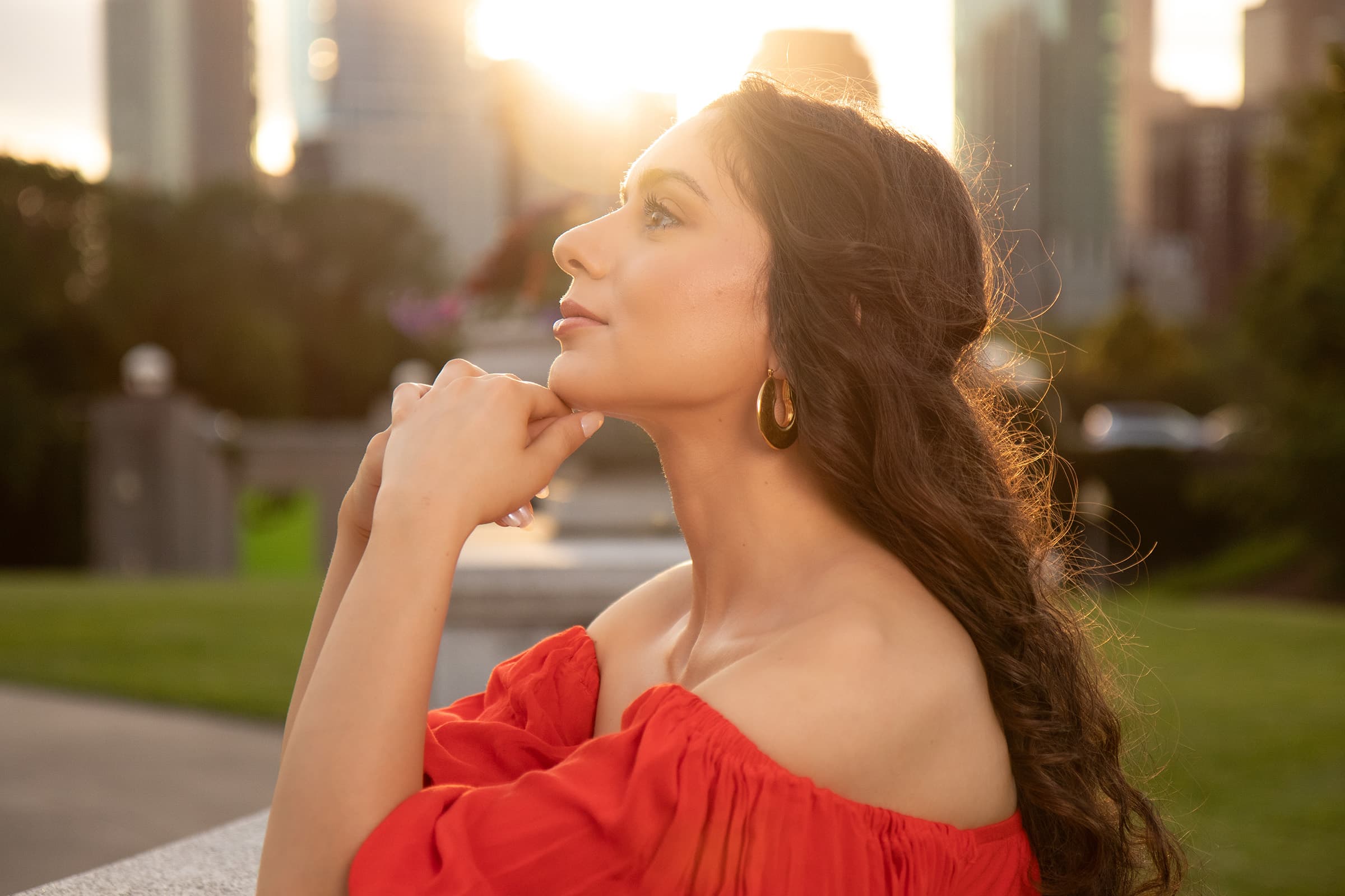Golden-hour outdoor portrait of a professional woman in Tampa, photographed in a red dress with warm natural light.