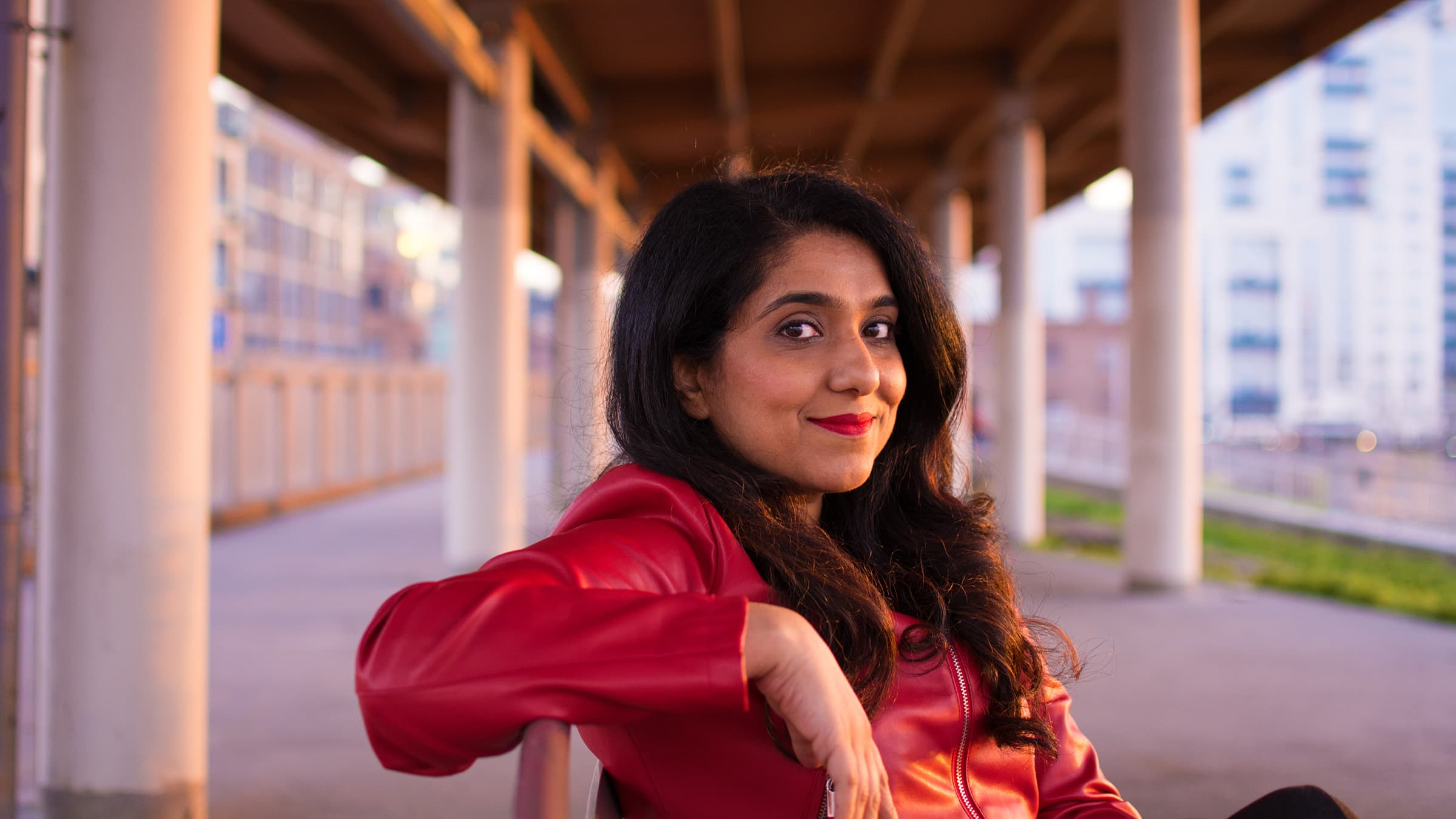 Professional outdoor portrait of a woman in a red leather jacket, photographed in Tampa with warm golden-hour light.